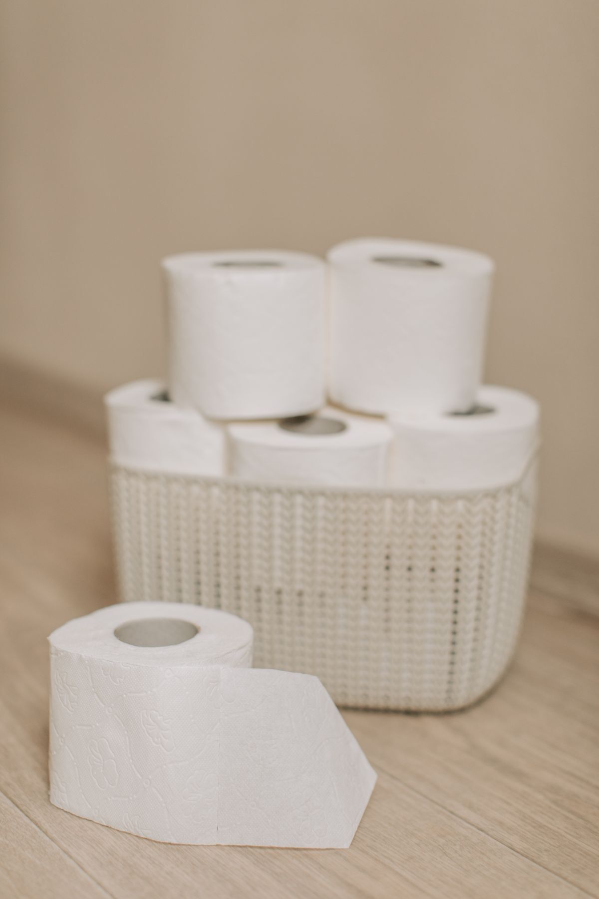 White toilet rolls stacked in a woven basket